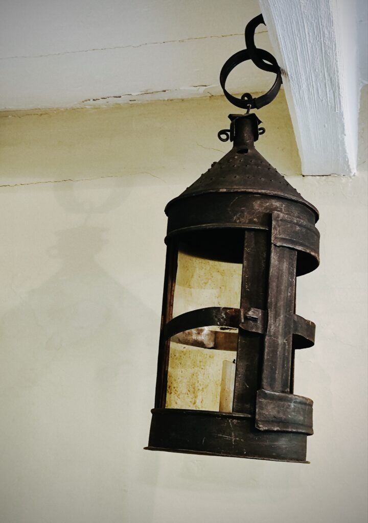 An old rusty metal lamp hanging from a beam